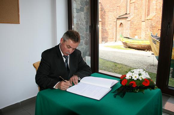 Obraz przedstawia Burmistrza Helu wpisującego się do księgi kondolencyjnej