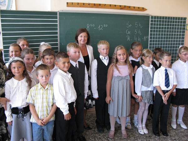 Obraz przedstawia uczestnictowo Marii Kaczyńskiej w inauguracji nowego roku szkolnego w Zespole Szkół Ogólnokształcących w Helu